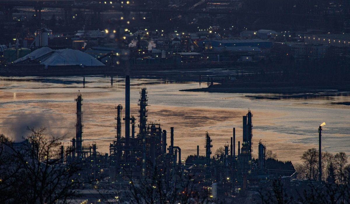 Ölraffinerie am Fluss in der Abenddämmerung – Aramco räumt Zentrale in Dhahran, Brent steigt über 114 Dollar