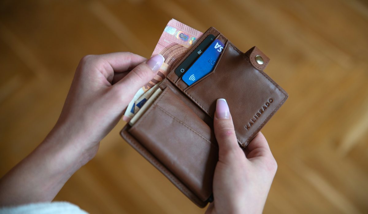 Person hält eine braune Leder-Kartenbörse mit Kreditkarten in warmem Licht – Titelbild zum Artikel Privatkredit Berlin 2026